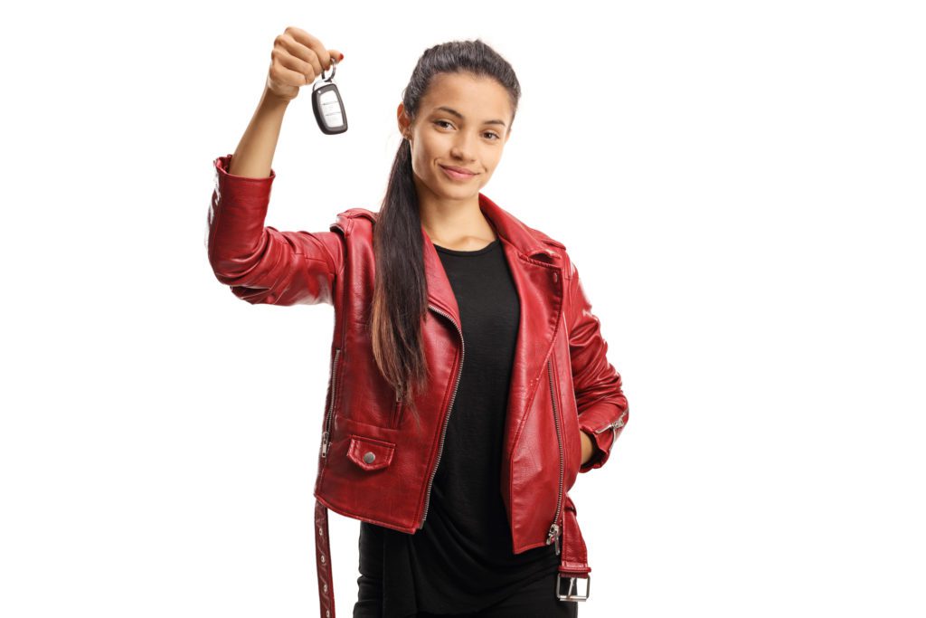 Young mixed race female holding a car key isolated on white background.